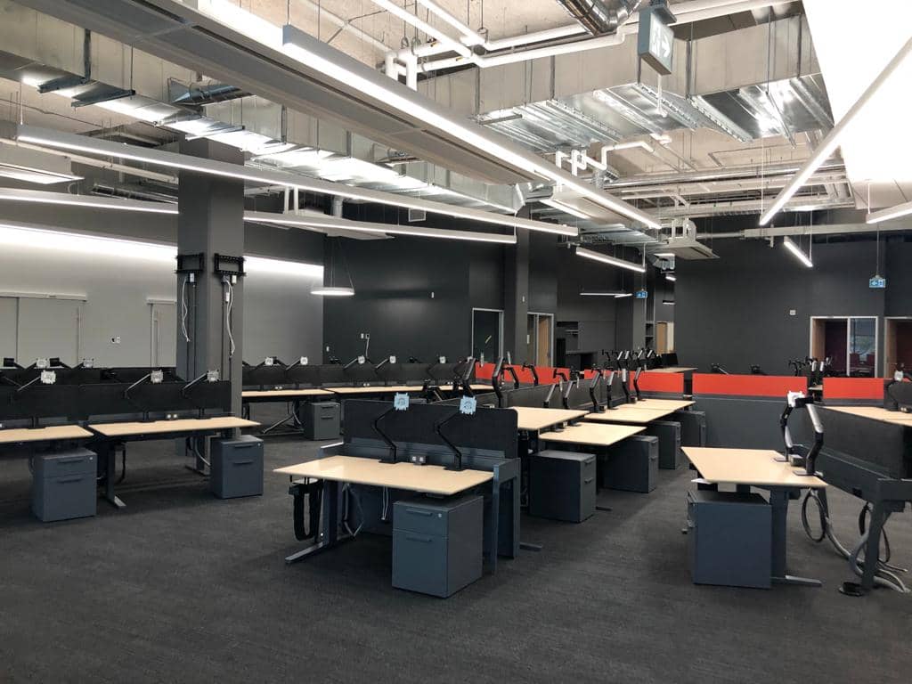 Espace de travail corporatif à aire ouverte installé par Noova Express, avec bureaux ajustables en hauteur et écrans de confidentialité